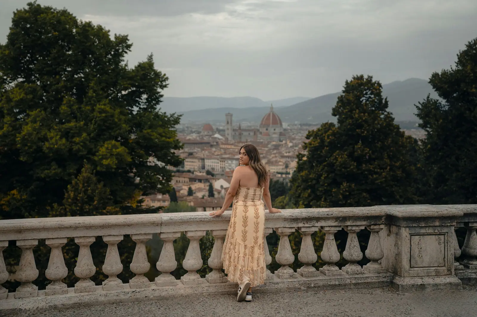 Eine Frau lehnt an einer Steinbalustrade und blickt über die Dächer von Florenz