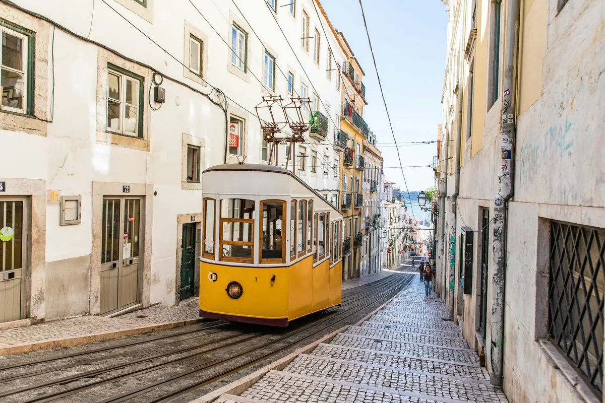 Die gelbe Standseilbahn Elevador da Bica in einer steilen Gasse in Lissabon